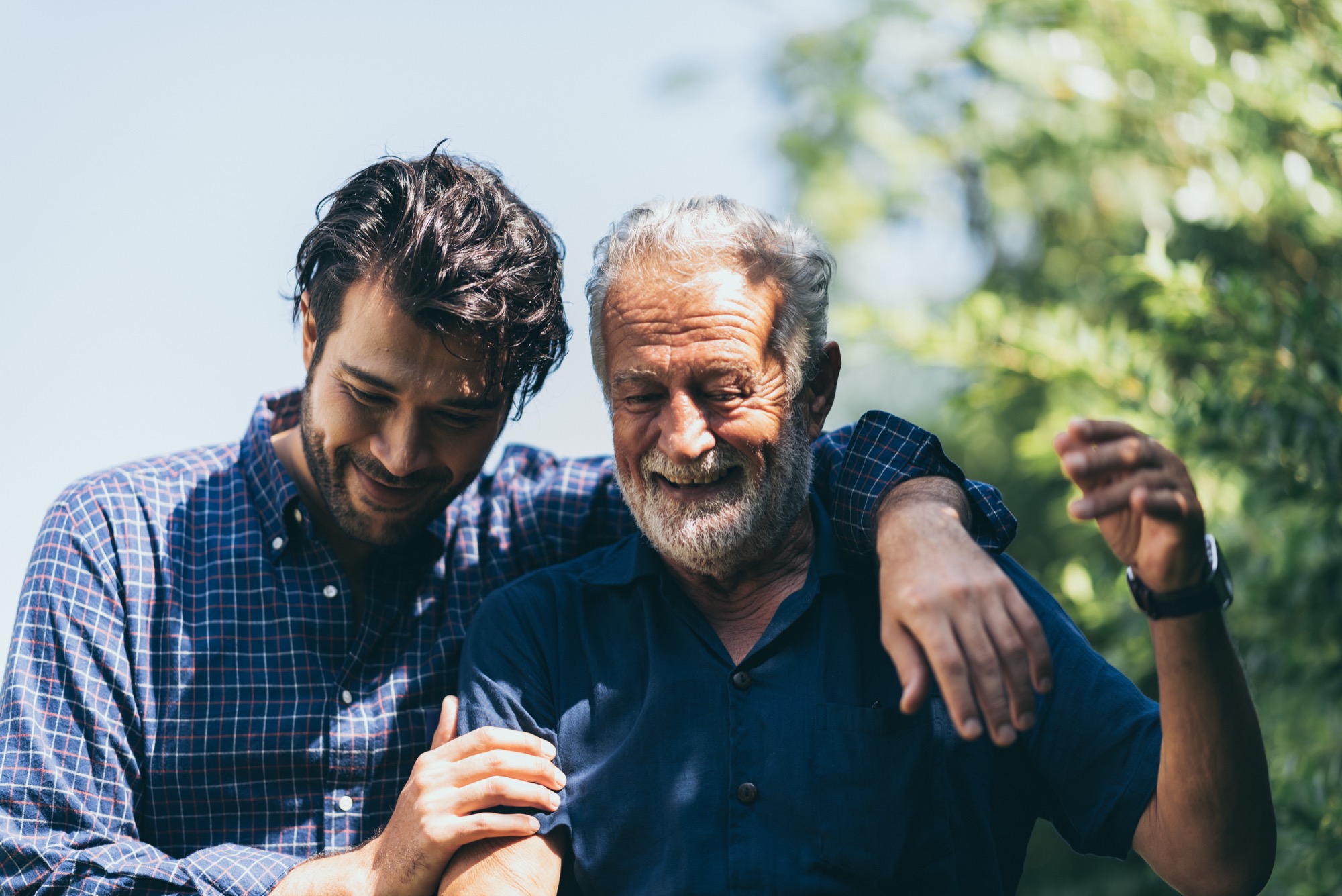 An adult son and older father sharing a warm outdoor moment